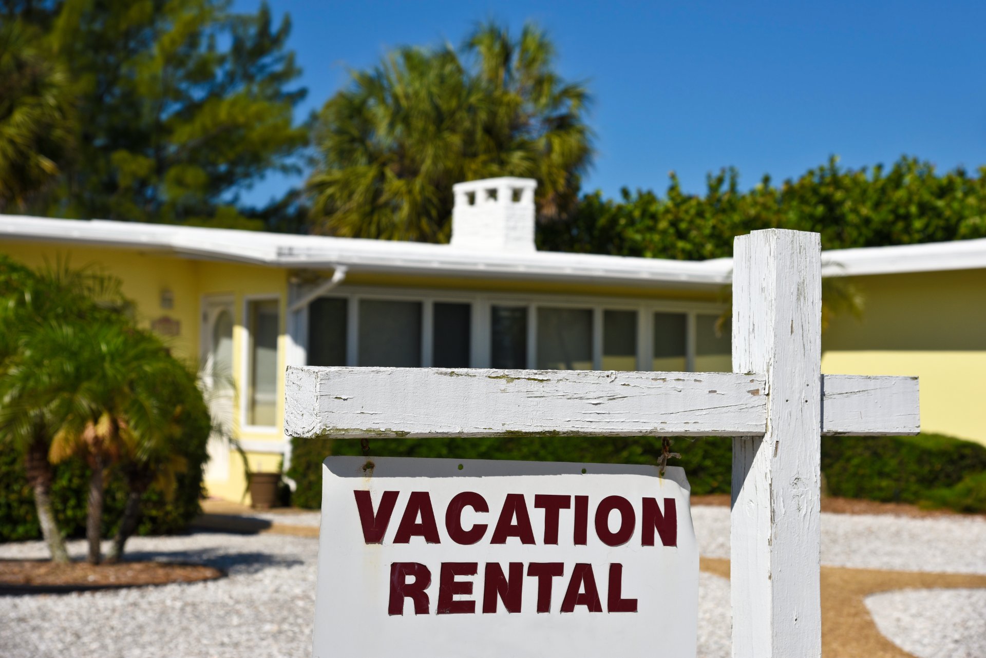 Yellow house with "vacation rental" sign in front yard