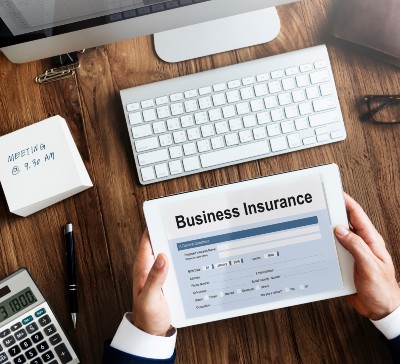 Overhead shot of man sitting at desk holding a tablet with a business insurance form on the screen - test case