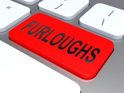 Man presses red "furlough" button on computer keyboard - furlough scheme