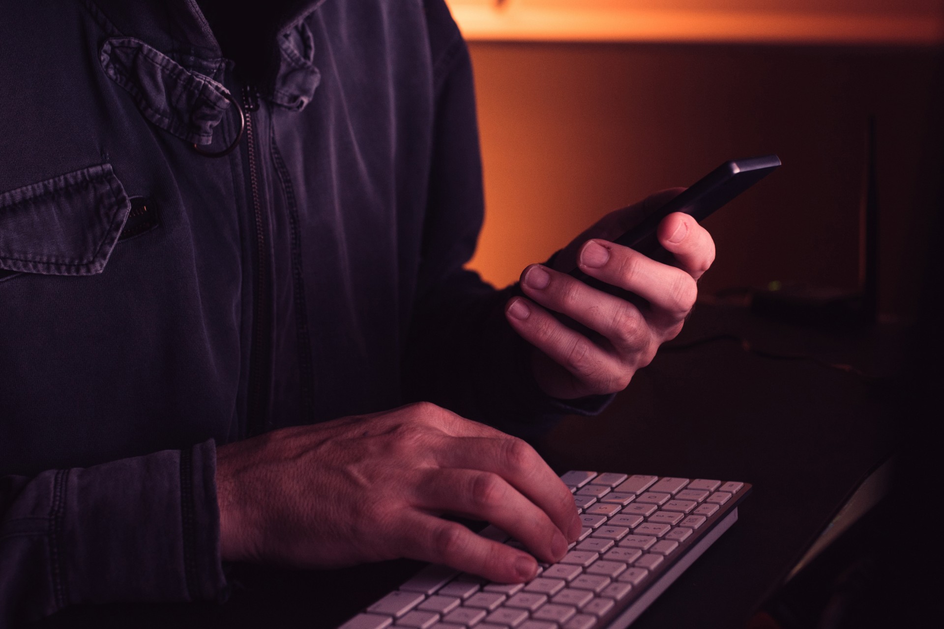 Man uses smartphone with left hand and keyboard with right hand - Amazon phone scam