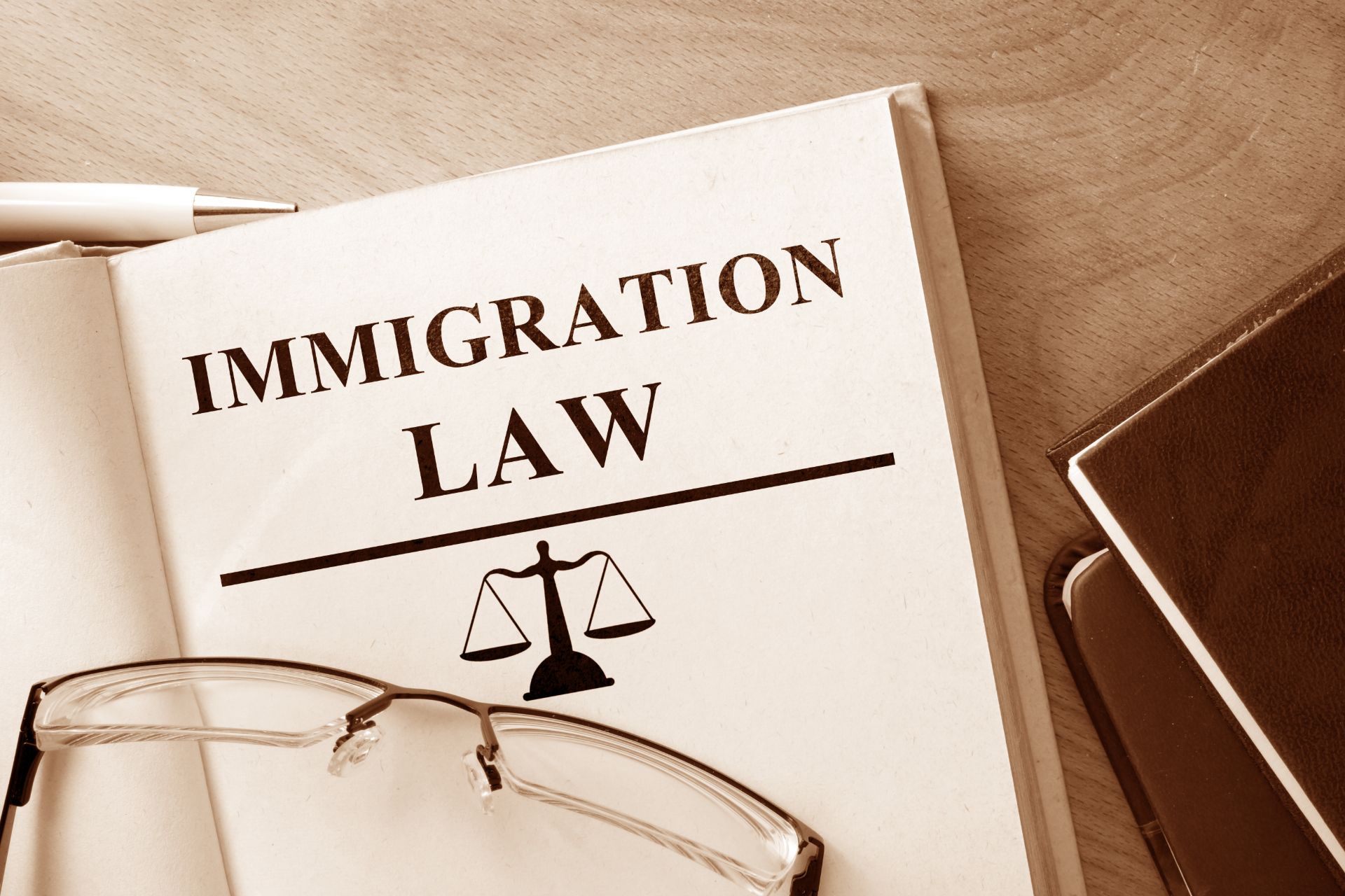 An immigration law book sits open with glasses lying on top - deportation to uganda