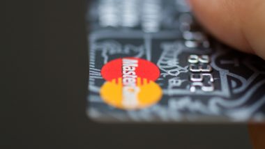 Mastercard logo on an orange credit card - mastercard class action lawsuit