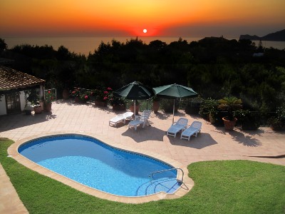 Pool in yard near body of water at sunset - Cottages.com