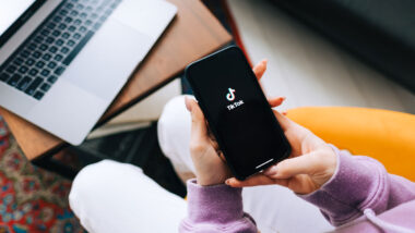 woman holding iPhone with TikTok app logo on the screen.