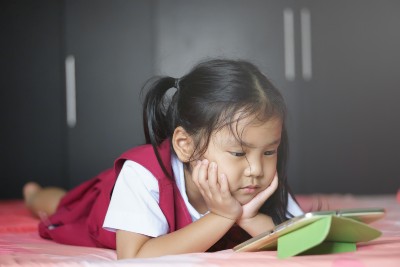 Young girl lies on stomach watching something on a tablet - Youtube privacy